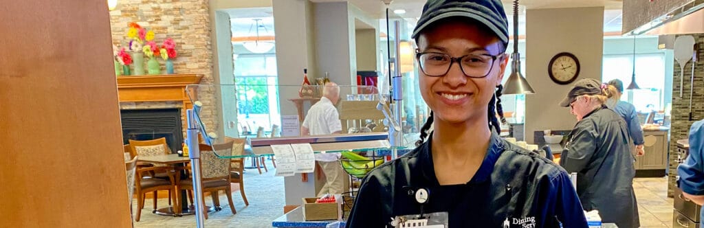Staff member in the dining area with a warm smile
