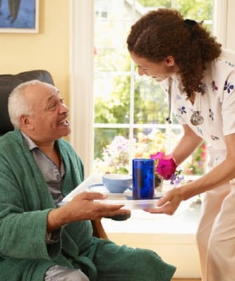 Caregiver serving food to a resident in a bright room