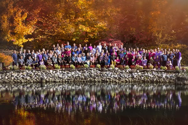 Staff and residents gathered by a pond during autumn
