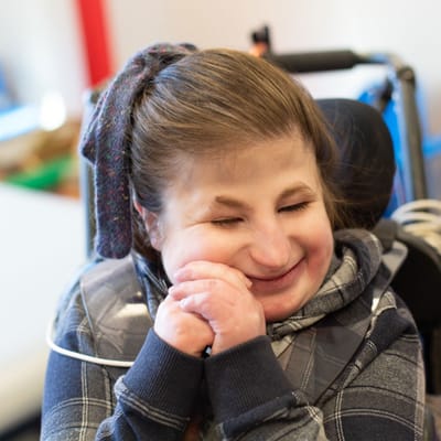 Smiling young woman in a wheelchair with clasped hands