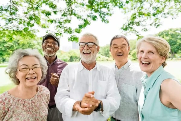 A group of smiling seniors enjoying a sunny day in the park