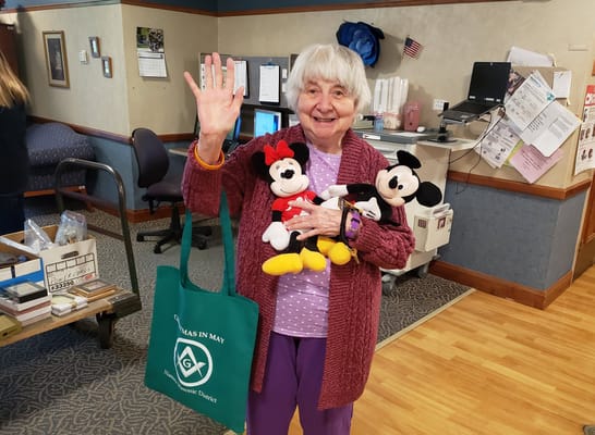 Senior resident holding stuffed toys and waving