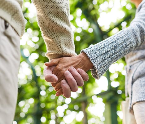 Close-up of two seniors holding hands in a garden