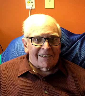 A smiling resident sitting in a comfortable chair