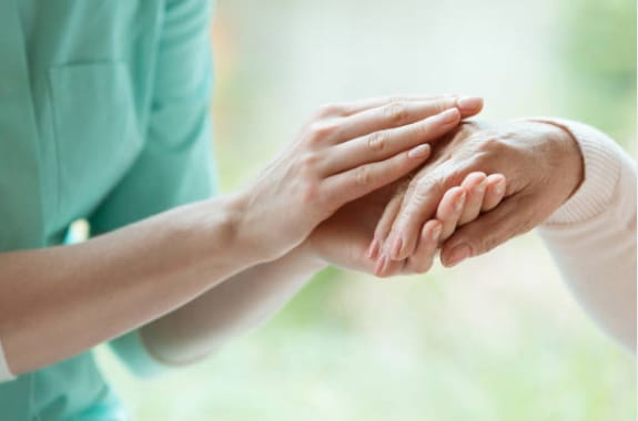 A caregiver holding a senior's hand with compassion