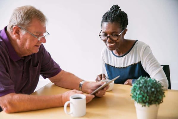Two residents engaged with a tablet at a table
