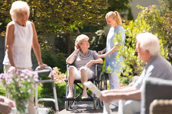 Residents enjoying time outdoors with staff assistance