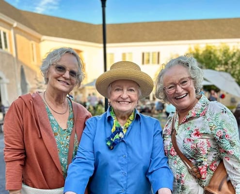 Three smiling women in a sunny outdoor setting