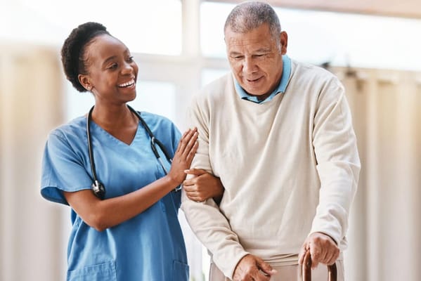 A nurse assisting an elderly man in a bright interior