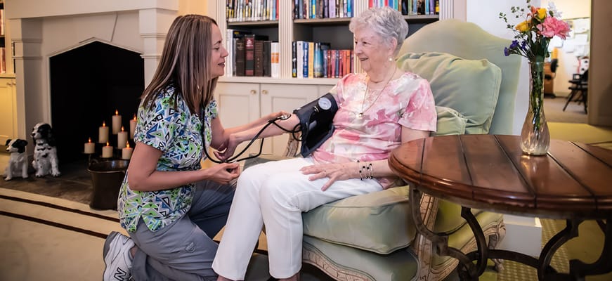 Caregiver taking a resident's blood pressure in a cozy sitting area