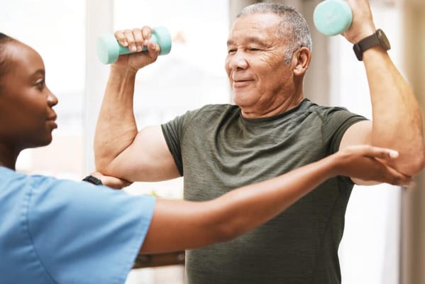 A trainer guiding a senior with weights in a bright room