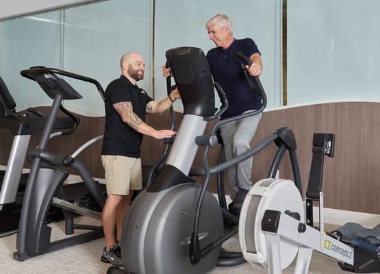 Trainer assisting a resident on exercise equipment