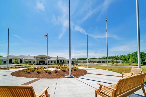 Exterior view of the assisted living facility with benches and flags