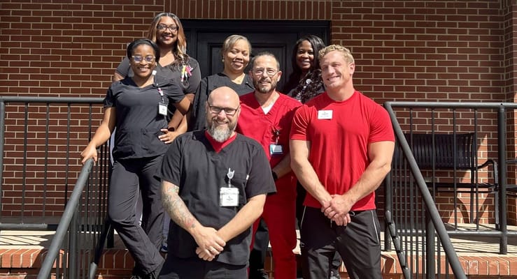 Staff members smiling together on the steps of the facility