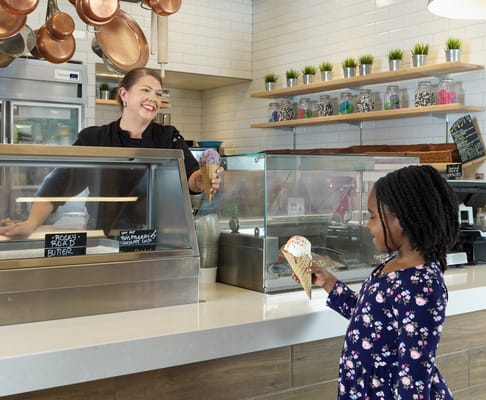 Staff serving ice cream to a child in a bright café area