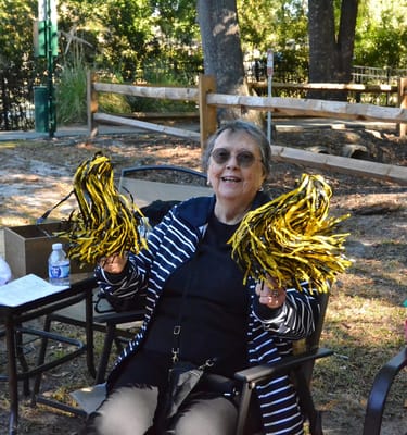 Senior woman cheerfully holding pom-poms outdoors