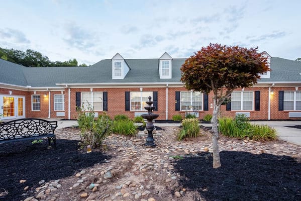 Exterior view of a senior living facility with garden and fountain