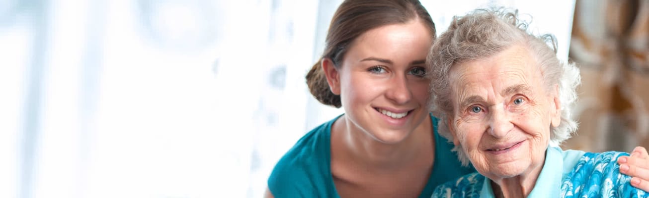 A caregiver embracing a smiling senior resident