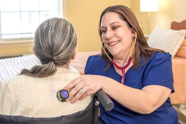 A healthcare worker assesses a resident with a stethoscope