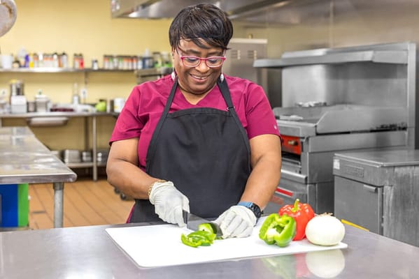 Staff member preparing vegetables in a kitchen