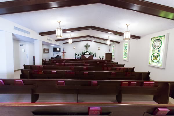 Interior view of a chapel with pews and stained glass windows