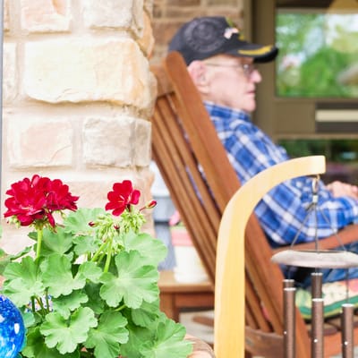 Senior resident relaxing on a porch with flowers