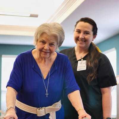 Resident walking with staff assistance in a bright interior