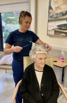 Staff styling a resident's hair in a cozy interior