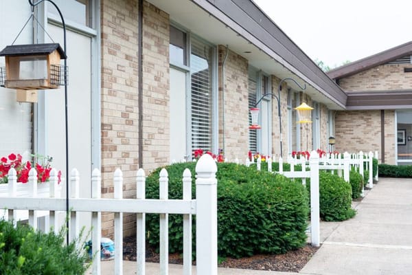 Exterior view of a senior living facility entrance with gardens