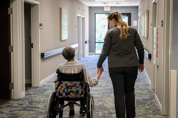 Caregiver assisting a resident in a hallway