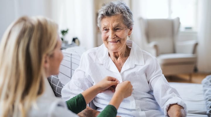 A caregiver assisting a smiling resident in a cozy living room