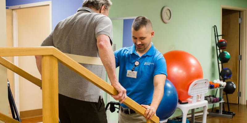 Staff assisting a resident with stairs in a therapy room