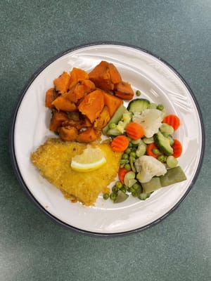 A plate of fish and vegetables served in a dining area