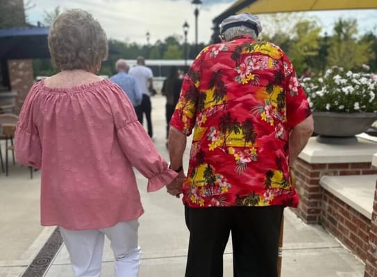 Two residents walking hand in hand outside the facility