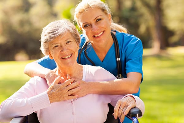 A caregiver and resident smiling in a garden