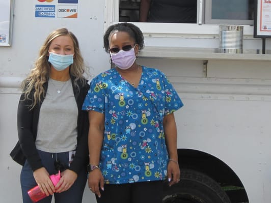 Two staff members in front of a food truck