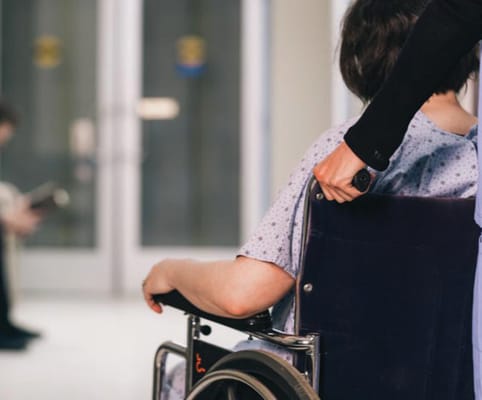A resident in a wheelchair being assisted indoors