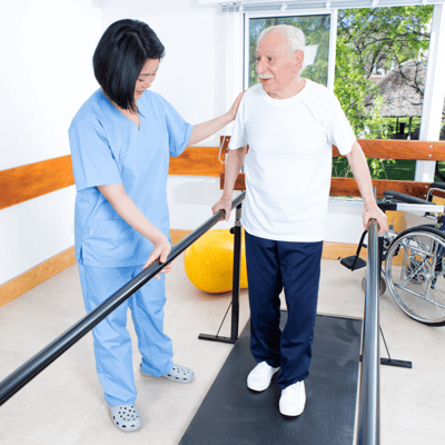 A caregiver assisting an elderly man on a walking apparatus