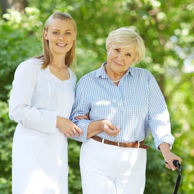 A caregiver assisting a senior woman outdoors