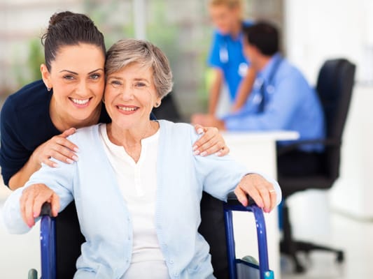 Caregiver smiling with a resident in a wheelchair