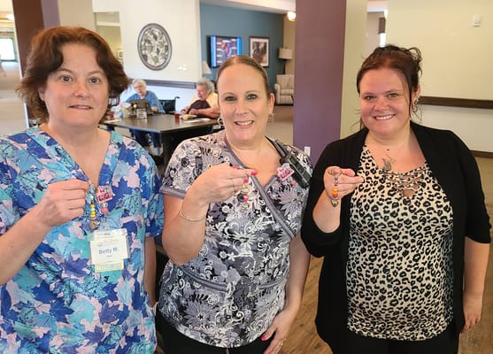 Three staff members smiling and displaying colorful beads