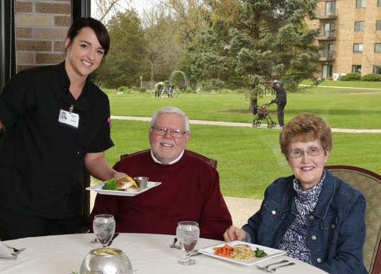 Residents enjoying a meal with staff in a dining area