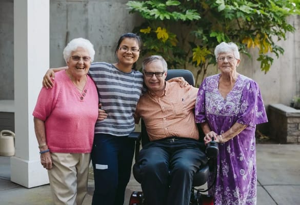 Four residents and a staff member smiling outdoors