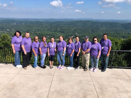 Group of staff members posing outdoors with a scenic view