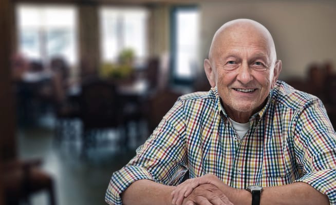 A senior man smiling in a cozy dining area