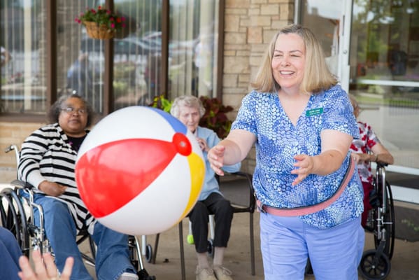 Staff engaging residents in an outdoor activity with a beach ball