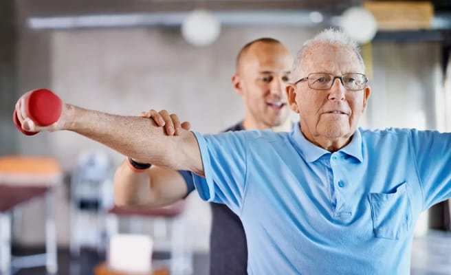Senior resident exercising with staff assistance