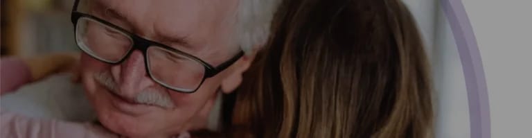 An elderly man joyfully embracing a young girl