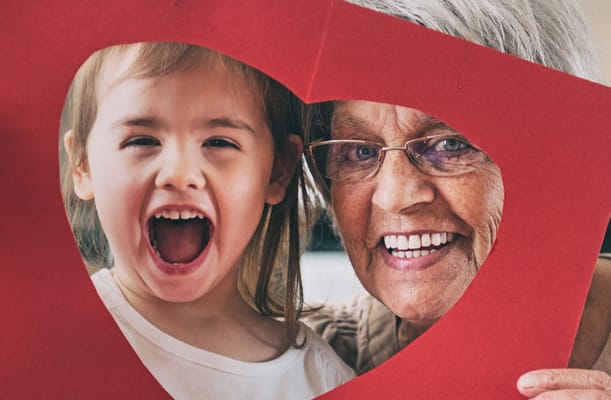 An elderly woman and a young girl smiling through a heart frame