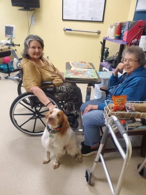 Residents enjoying a game with a dog in an activity room